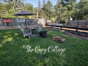 A backyard with a grill, chairs, and a sign for 'The Cozy Cottage'. - Private Cottage to nurture the soul (MIRAMONTE)