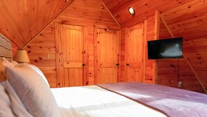 Une pièce de cabane en bois comprenant un lit, un téléviseur et des murs en bois.