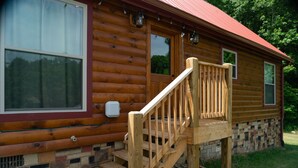 Une cabane en rondins avec un escalier en bois menant à une véranda.
