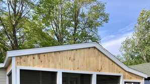 Une petite construction en bois d’un seul étage, dotée de grandes fenêtres et de jardinières en bois à l’extérieur.