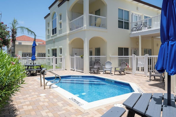A pool area with a 3 FT diving board, lounge chairs, and a covered seating area.
