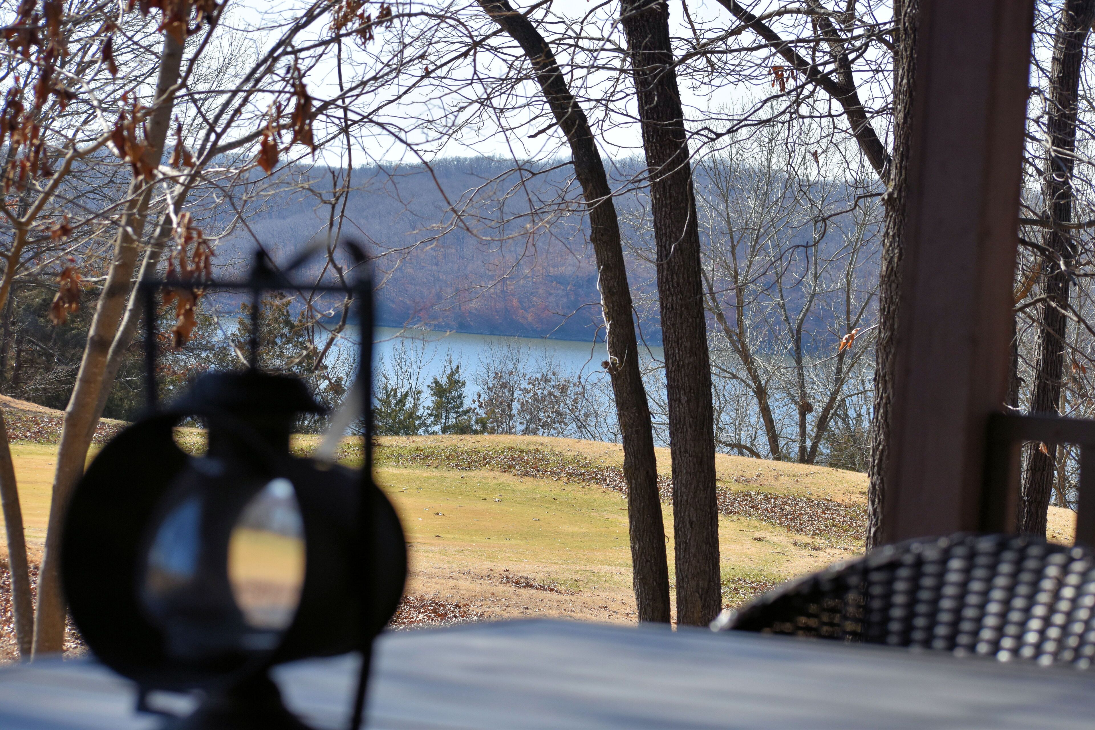 A view from a porch overlooking a lake with trees and a distant mountain range.