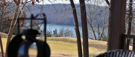 A view from a porch overlooking a lake with trees and a distant mountain range.