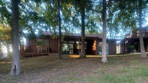 A modern building with a covered patio area, surrounded by trees.