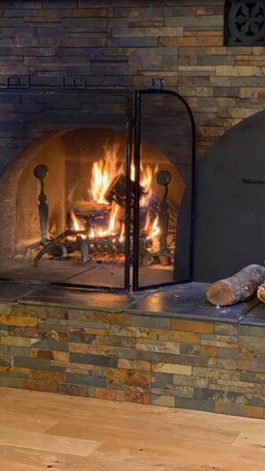Cozy warmth is found in this inviting fireplace, complete with a fire screen and a log on the hearth.