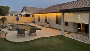 A backyard with a swimming pool, two chairs, a barbecue area, and a covered patio. - Great home in fantastic location! Close to everything! Heated pool! (Chandler)