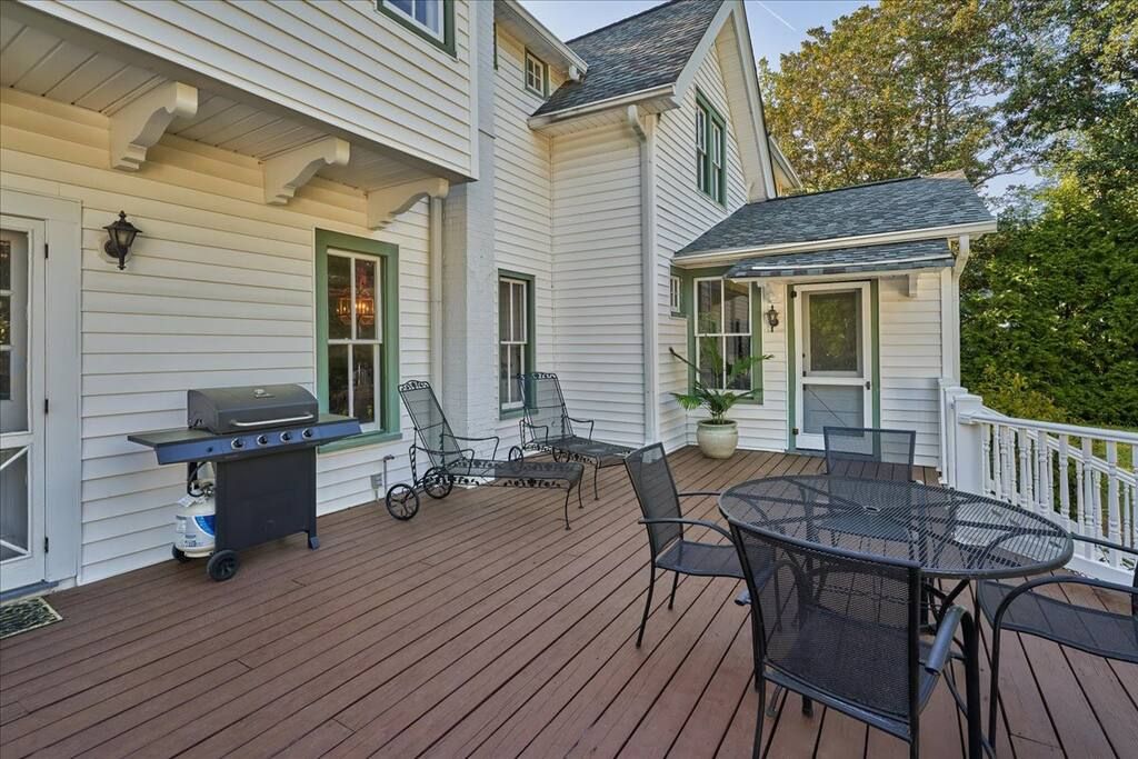 Une terrasse en bois avec un barbecue, des chaises et une table.