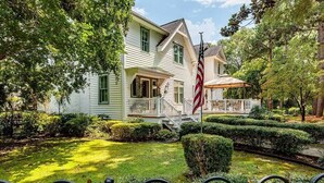 A two-story house with a front porch, a flag, and a well-maintained garden. - ★ LUXURY 5 BR VILLA Heart of Village Steps From #2 (Pinehurst)