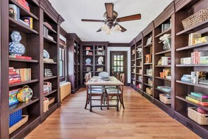 Una biblioteca con estanterías de madera, una mesa central y sillas.