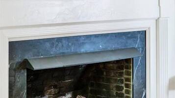 A fireplace with a marble surround, a round mirror above it, and wall sconces with candles.