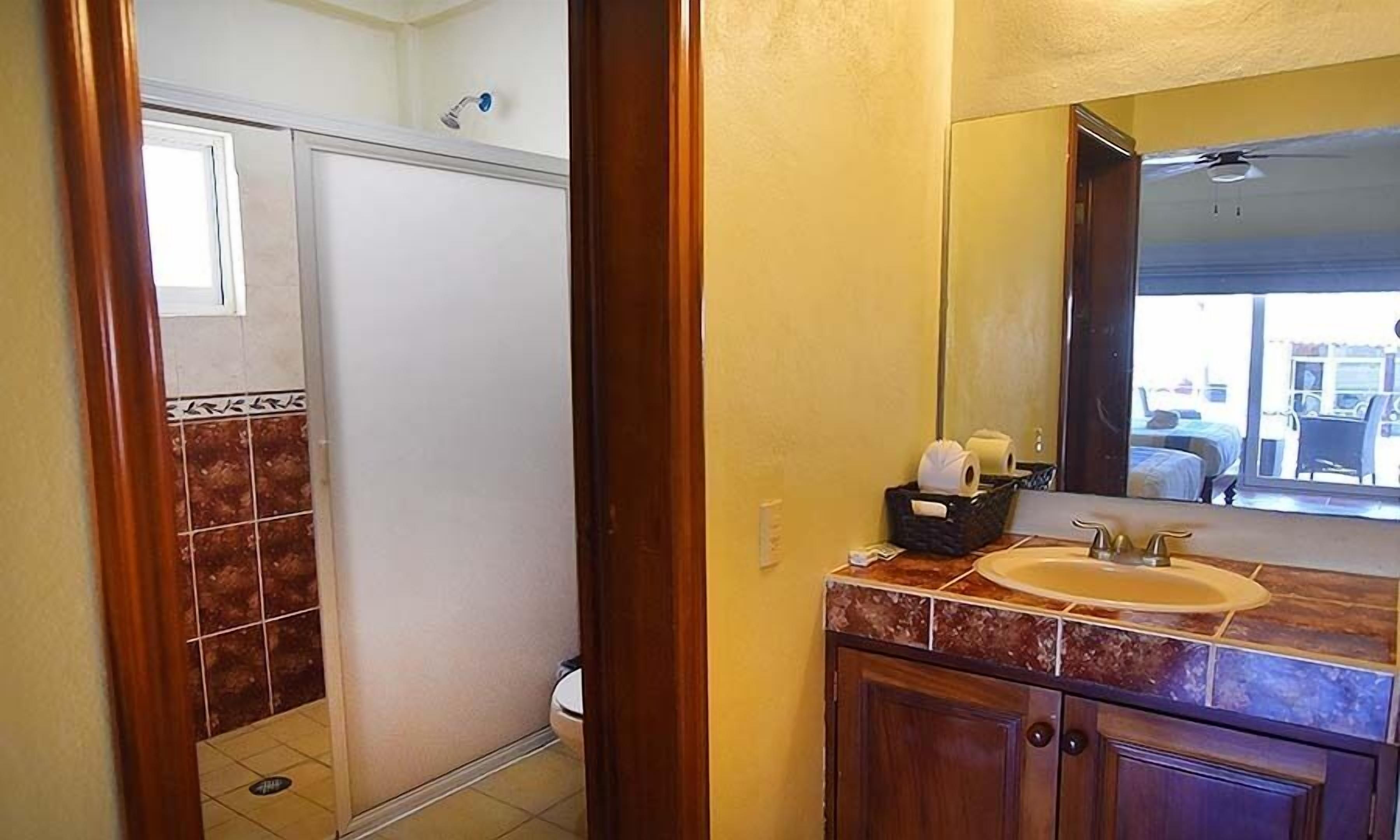 Un baño con ducha, lavabo y espejo.
