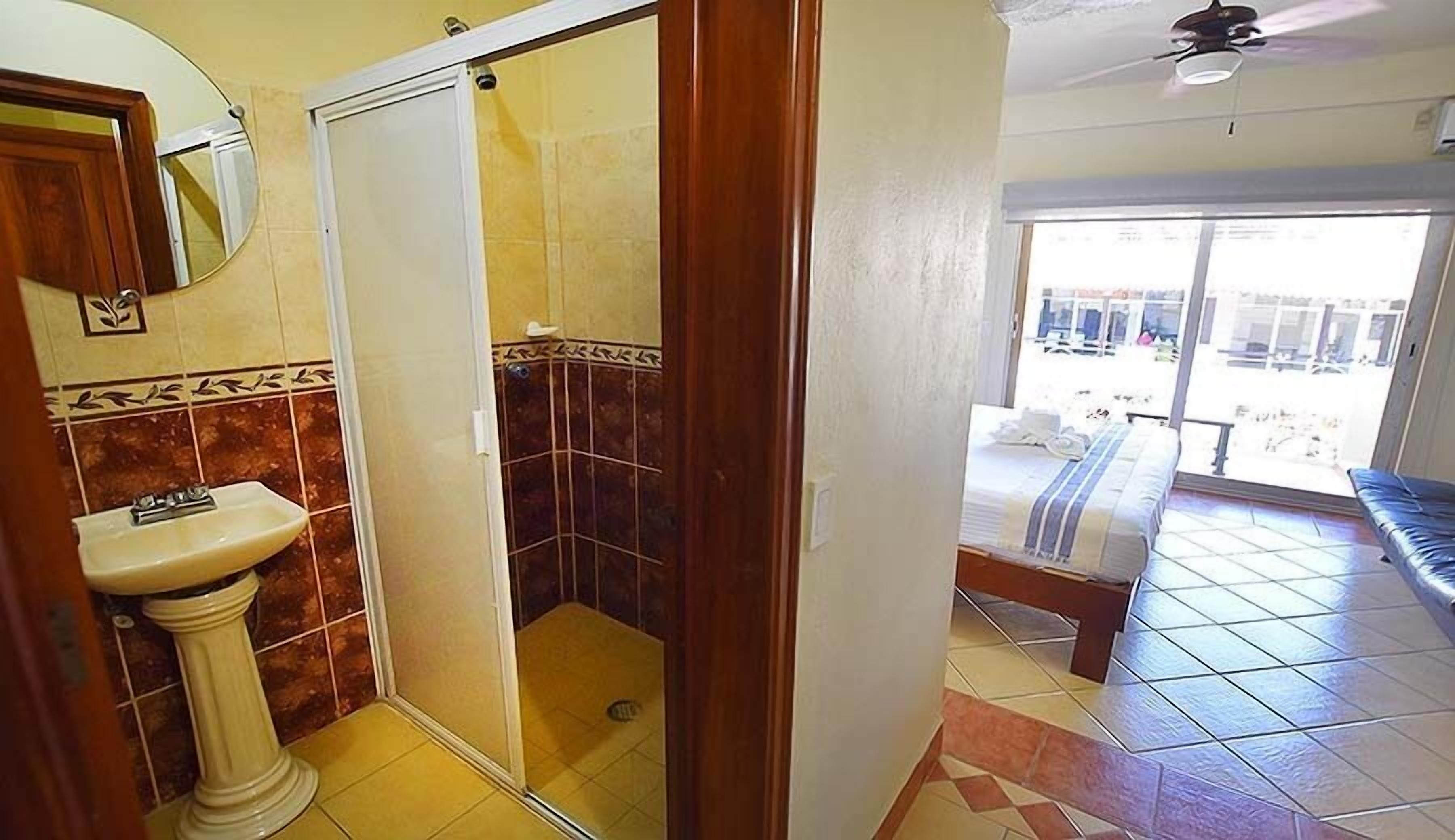 A bathroom with a sink, shower, and a view of the outside.