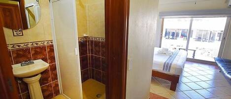 A bathroom with a sink, shower, and a view of the outside.