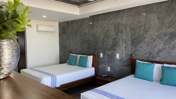 Habitación de hotel con dos camas, un ventilador de techo y una planta sobre una mesa.