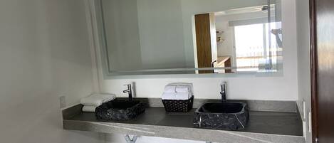 A modern bathroom with two sinks, a large mirror, and a towel rack.