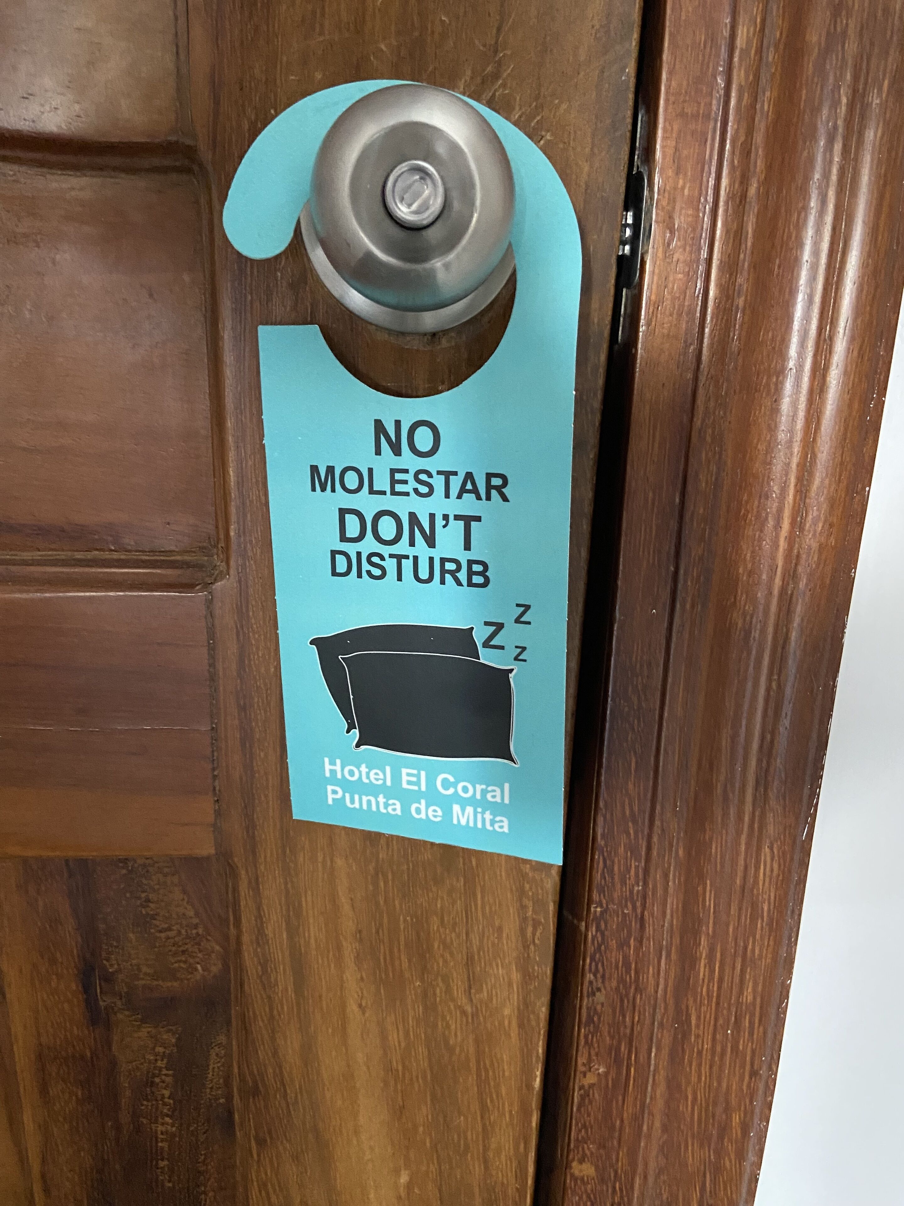 Una puerta con un letrero que dice 'NO MOLESTAR DON'T DISTURB' y 'Hotel El Coral Punta de Mita'.