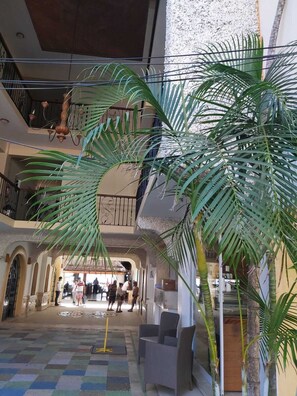 Un vestíbulo espacioso con piso a cuadros, una escalera y una palmera grande.