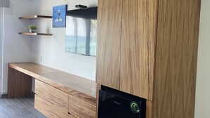 Een moderne keuken met houten keukenkasten, een inbouwvaatwasser en uitzicht op de oceaan door grote ramen.