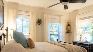 Un dormitorio con cama, ventilador de techo y ventana con cortinas.