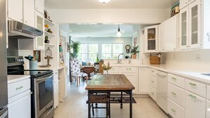 Una cocina moderna con armarios blancos, electrodomésticos de acero inoxidable y una mesa de comedor de madera.