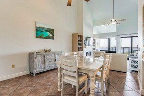 Un vaste espace dédié à la salle à manger, avec une grande table et des chaises, un buffet en bois et un tableau représentant un paysage côtier.