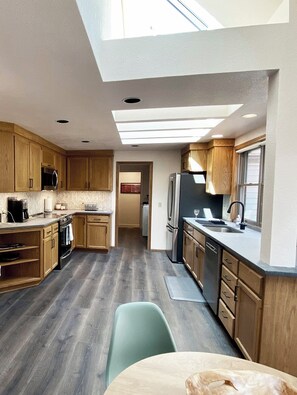 A modern kitchen with wooden cabinets, a built-in oven, a refrigerator, and a skylight. - Premier Neighborhood - Sleeps 10 - King Beds - .37 miles to Autzen - walk to UO (Eugene)