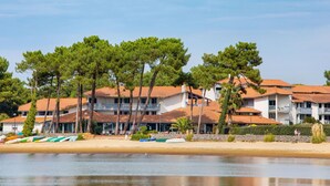 Ein Hotel an der Küste mit mehreren Gebäuden, einem Sandstrand und Booten.