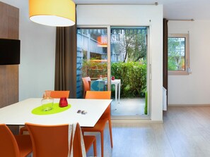 Et moderne spiseområde med et hvidt bord, orange stole og en gul lampe.