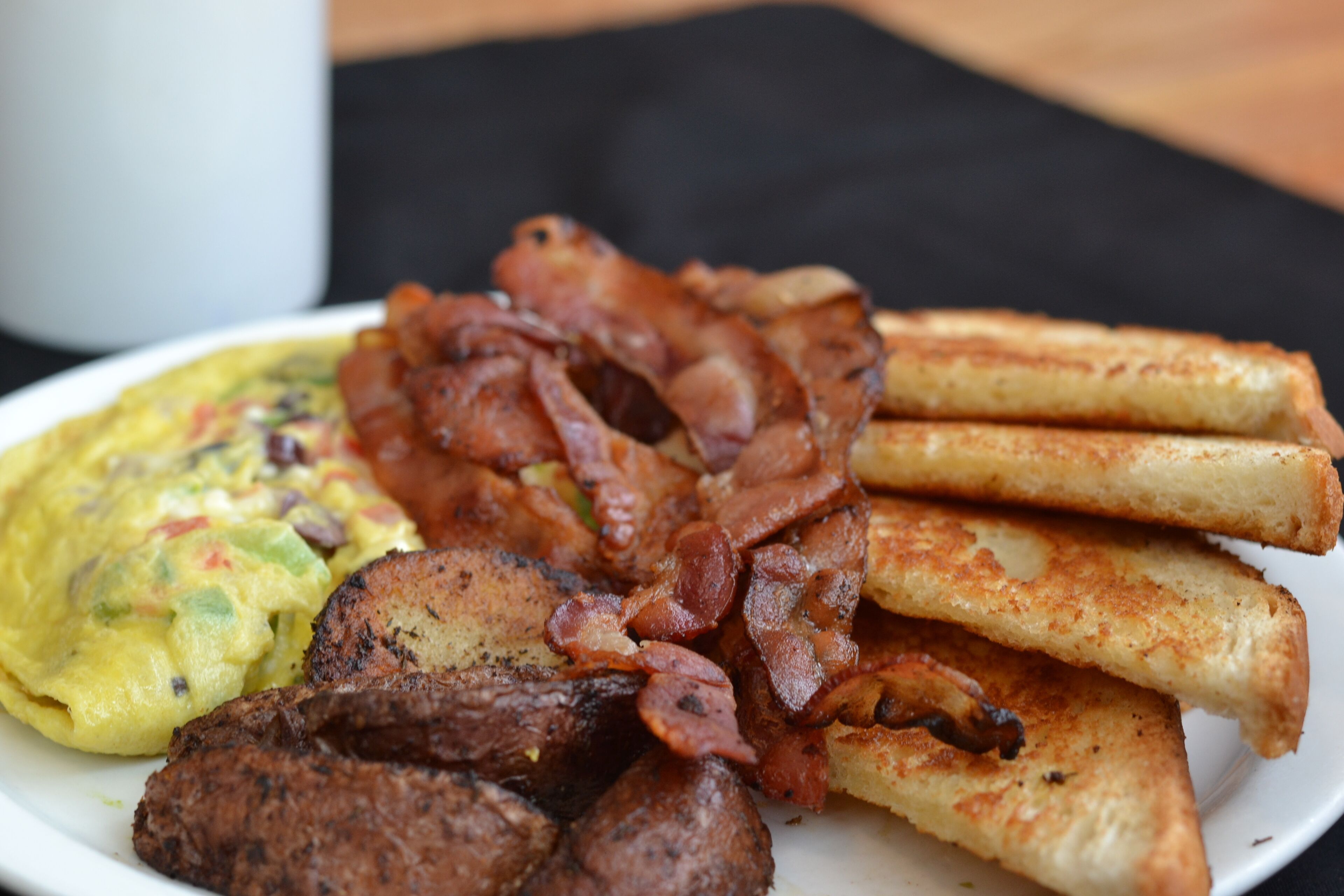 A plate of food including bacon, toast, and scrambled eggs.