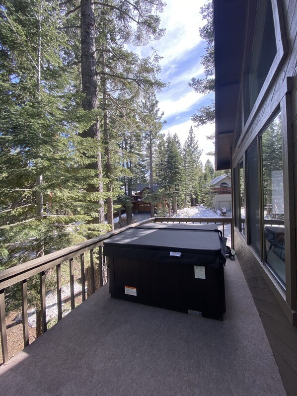 Enjoy a serene forest view from this balcony with a seating area and table.