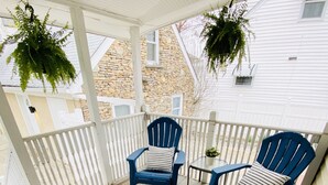 Un patio techado con dos sillas Adirondack azules y una mesita.