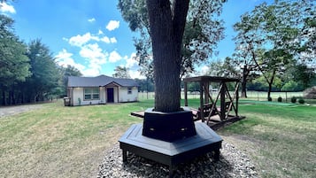 A house with a porch, a wooden deck, and a gazebo in a grassy yard.