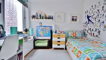 A child's bedroom with a desk, a bed, a bookshelf, and a wall with sports-themed decals.
