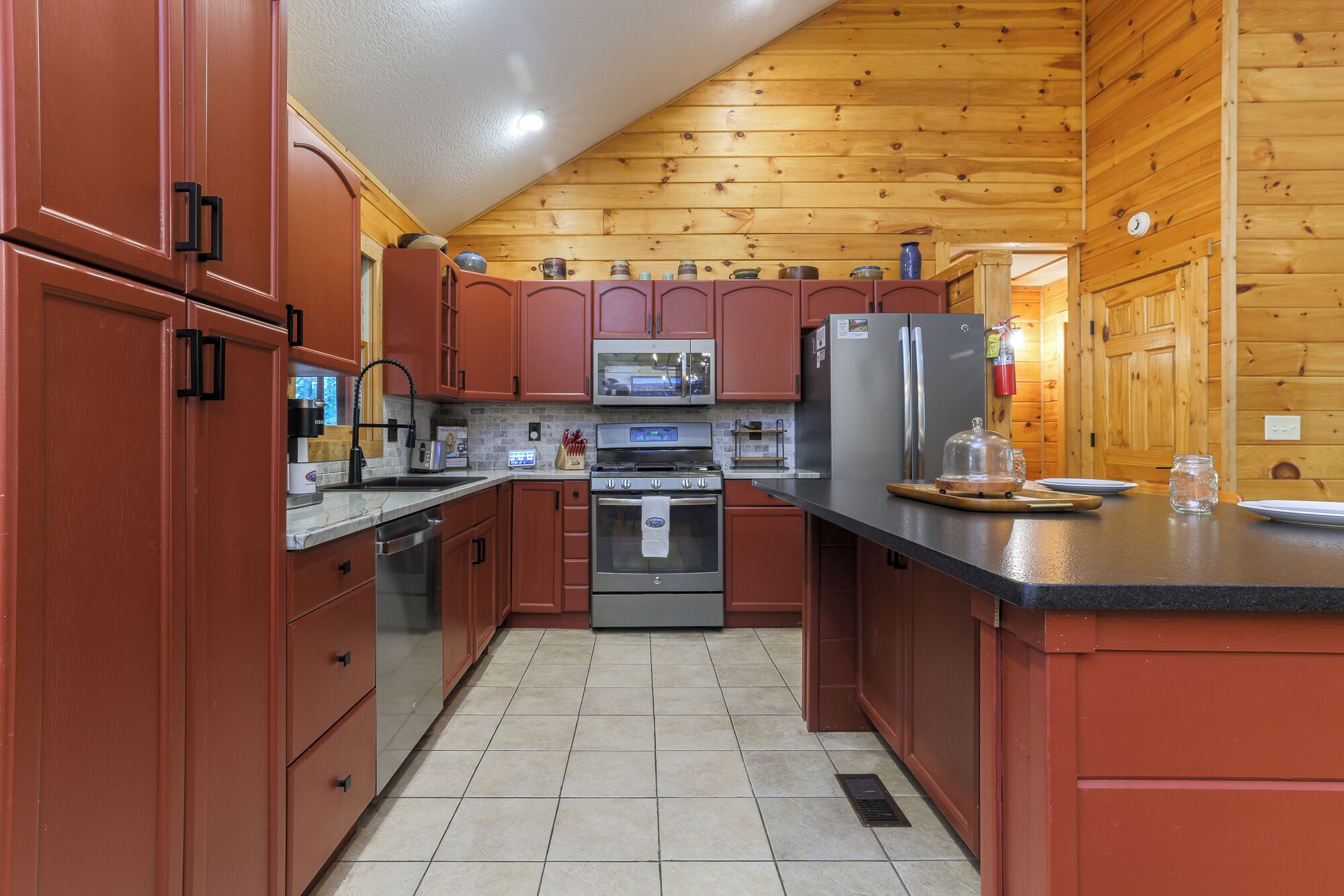 A kitchen with wooden cabinets, stainless steel appliances, and a tiled floor.
