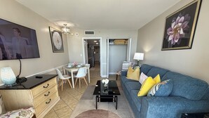 A living room with a sofa, coffee table, and a dining area with chairs and a table.
