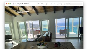 A spacious kitchen with a large island, a ceiling fan, and a view of the ocean through large windows. - Enjoy Caribbean Sun in Paradise with Privacy, Pool, and Panoramic View, Sleeps 8 (St Thomas)