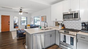 A modern kitchen with white cabinets, stainless steel appliances, and a central island with a dishwasher.