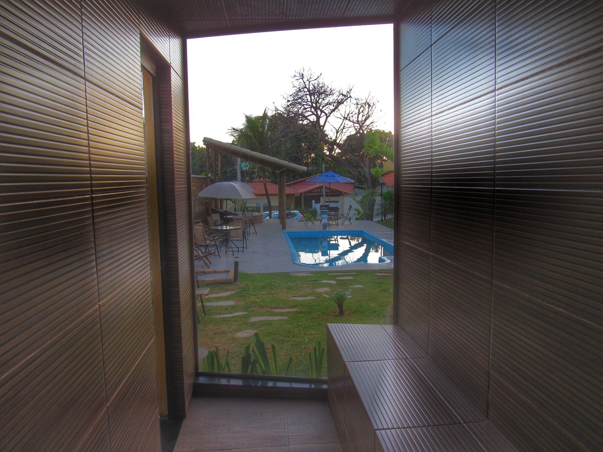 A view from a balcony with a pool and outdoor seating.