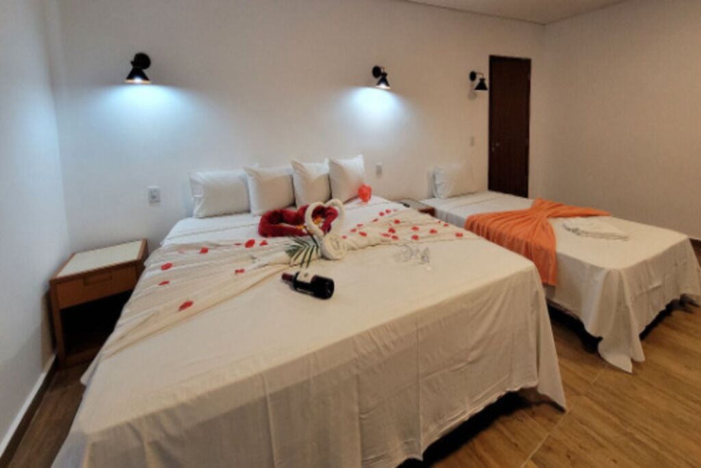 Een hotelkamer met twee bedden, een nachtkastje en een deur.