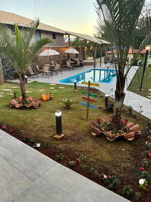 A pool area with a patio, outdoor furniture, and decorative plants.