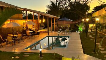 A pool area with a covered seating area and outdoor furniture.
