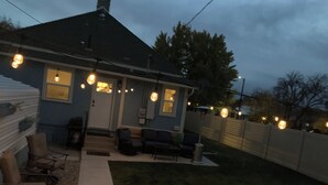 Una casa con un patio techado, mobiliario exterior y luces colgantes.