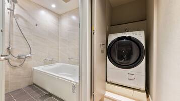 Un baño con ducha, bañera y lavadora de carga frontal.