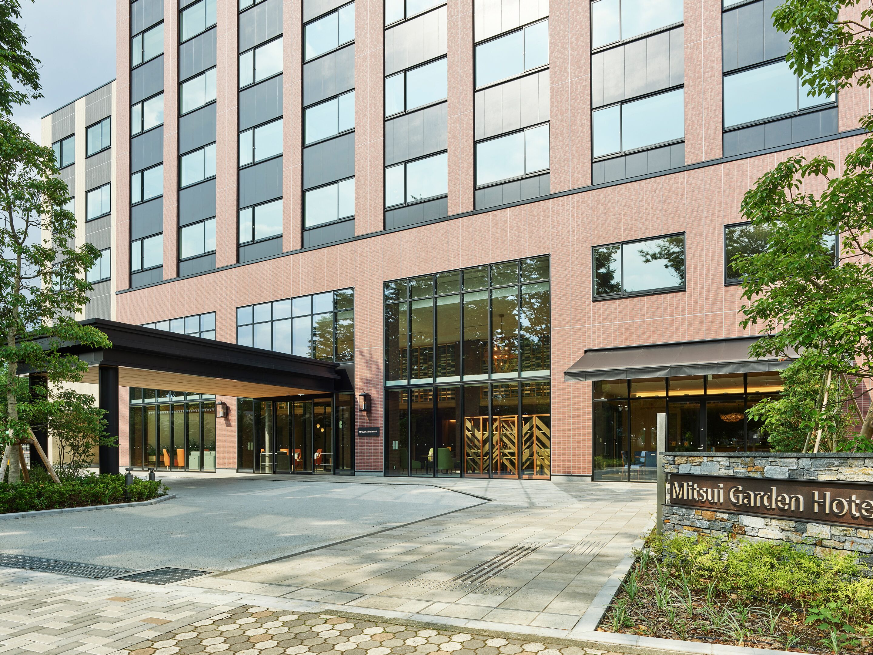 A modern hotel with a brick facade, large windows, and a covered entrance area.
