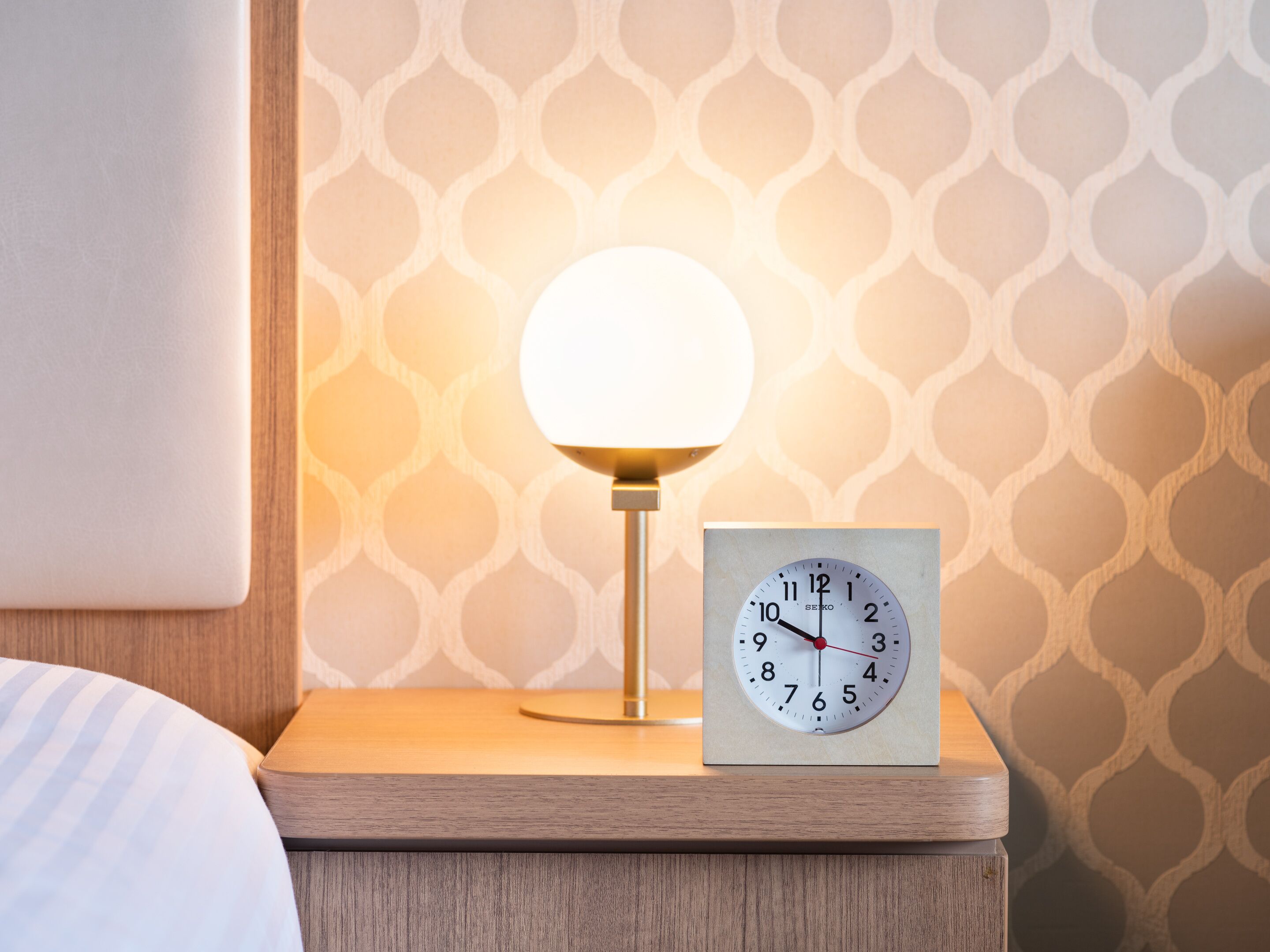 Une table de chevet avec une horloge et une lampe.