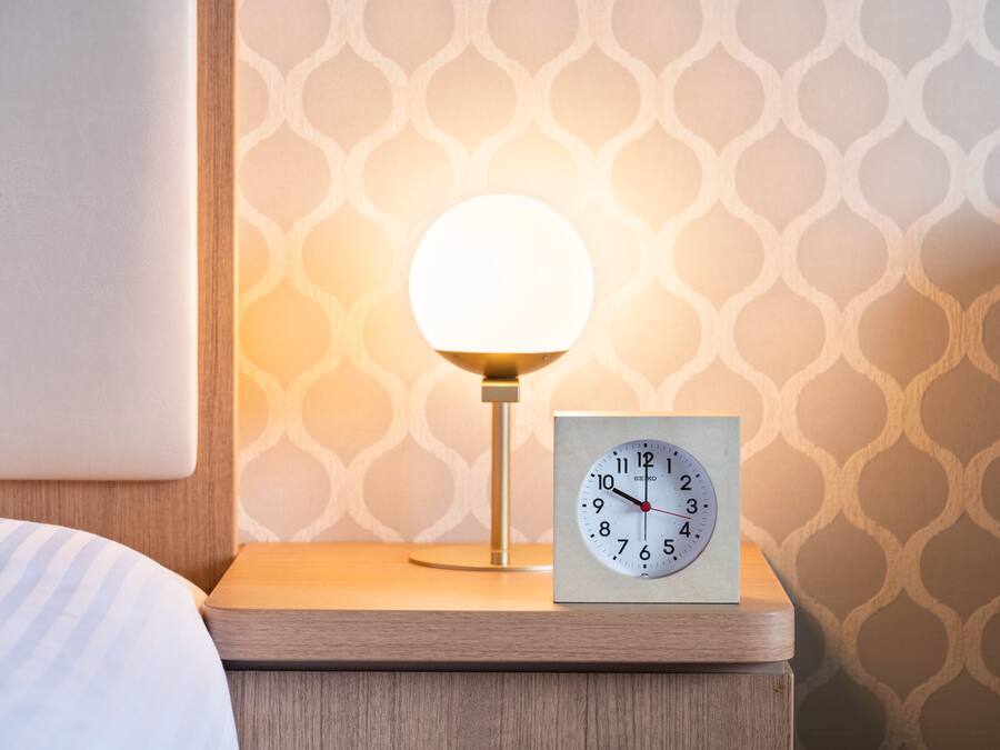 Une table de chevet avec une horloge et une lampe.
