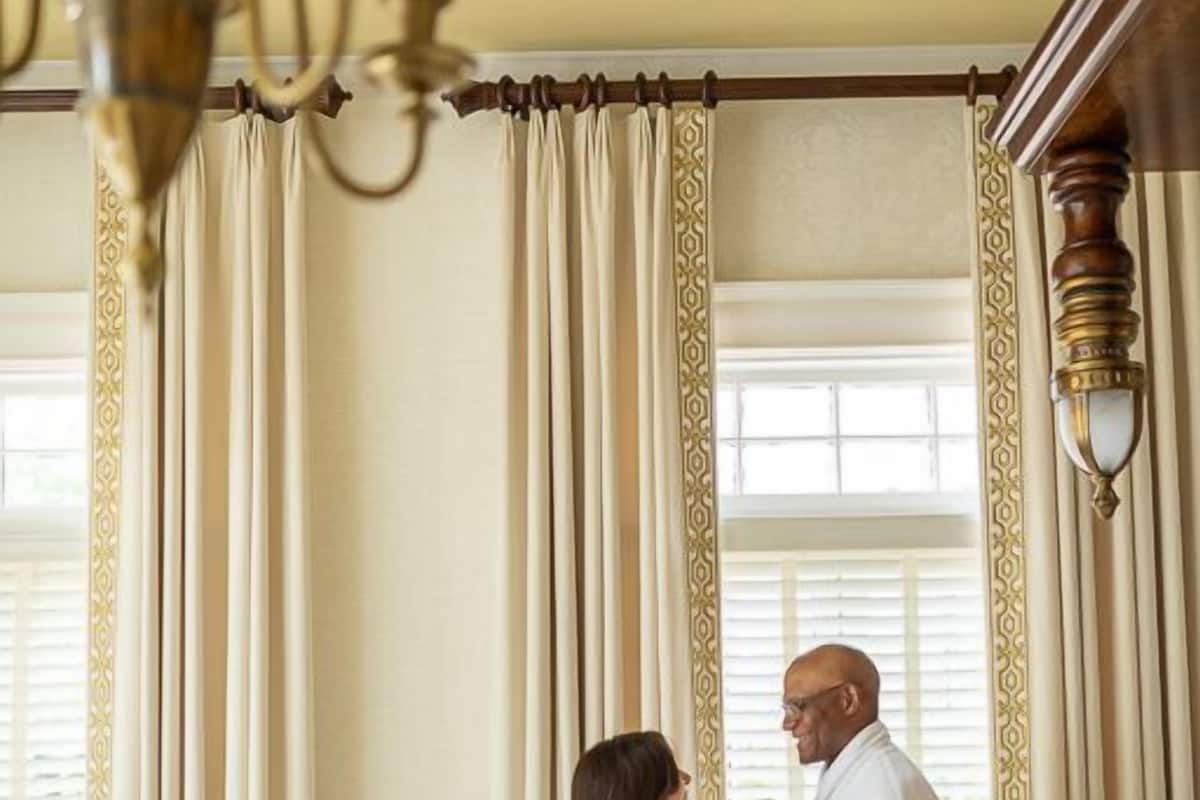 A hotel room with a bed, a chandelier, and curtains.