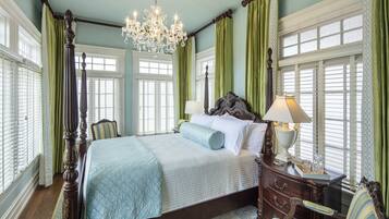 Un dormitorio con cama con dosel, candelabro y cortinas verdes.