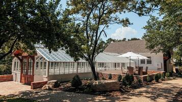 A greenhouse with a glass roof, surrounded by a brick patio and a gravel path.