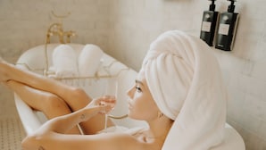 A person relaxing in a bathtub with a towel wrapped around their head, holding a glass. - The Reserve at Hot Springs (Hot Springs)